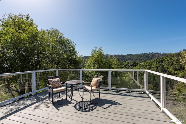 wooden terrace featuring a view of trees