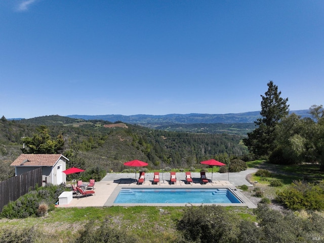 view of swimming pool featuring a fenced in pool, fence, a patio, and a mountain view