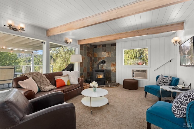carpeted living area featuring a wood stove, a wall mounted AC, beam ceiling, and a healthy amount of sunlight