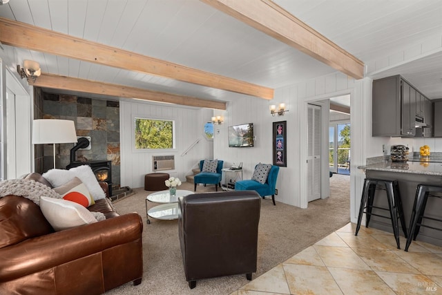 living area featuring light tile patterned flooring, beamed ceiling, a healthy amount of sunlight, and a wood stove