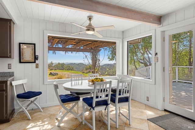 sunroom / solarium with beam ceiling, a mountain view, a wealth of natural light, and tile patterned flooring