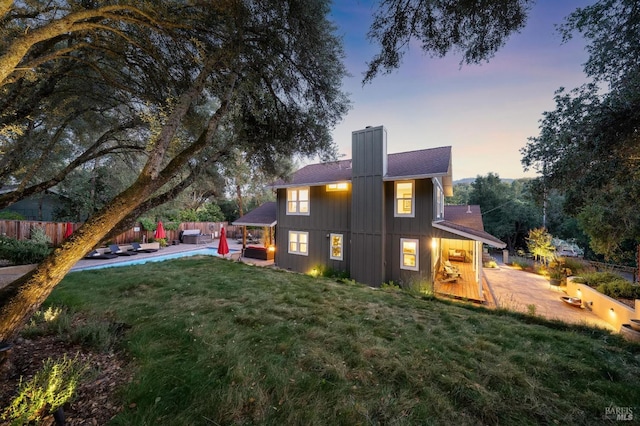 rear view of property featuring a patio, a chimney, fence, and a yard