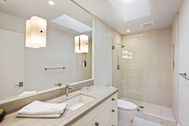 full bath featuring tiled shower, toilet, vanity, a skylight, and visible vents