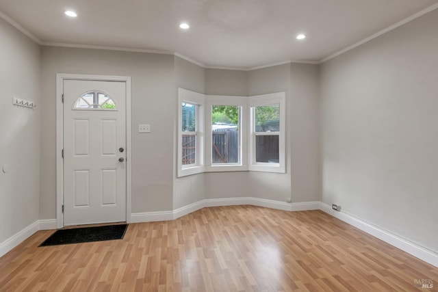 foyer featuring light wood-style floors, crown molding, and baseboards
