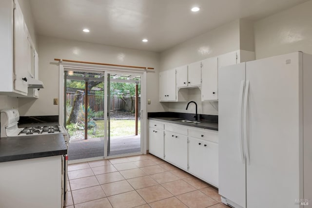 kitchen featuring light tile patterned floors, a sink, dark countertops, and white appliances