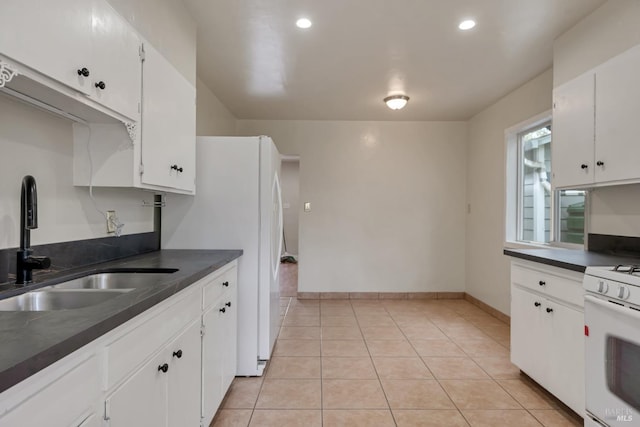 kitchen with white cabinets, a sink, dark countertops, and white appliances