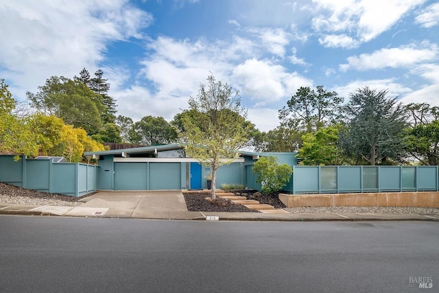 mid-century inspired home featuring fence, a garage, and concrete driveway