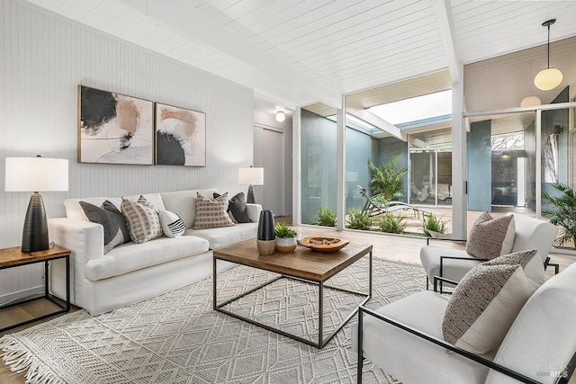 living room with beam ceiling, a wall of windows, and wood finished floors
