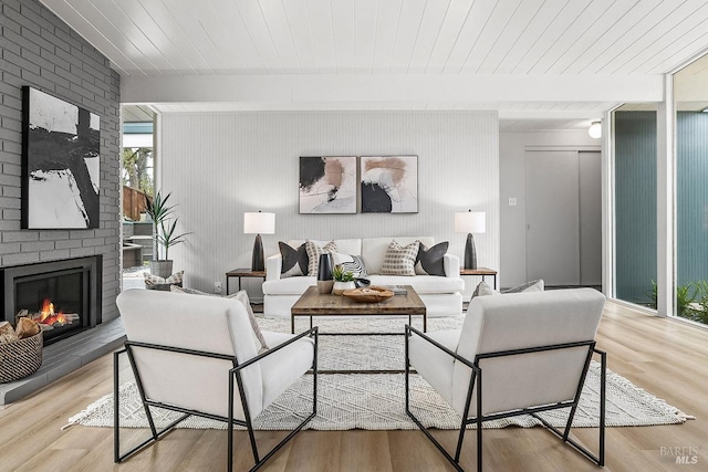 living room with wood finished floors, beam ceiling, wooden ceiling, and a brick fireplace