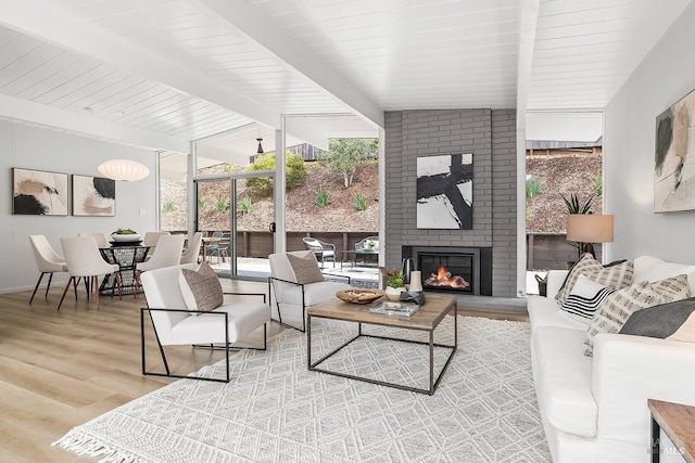 living area with vaulted ceiling with beams, expansive windows, wood finished floors, and a fireplace