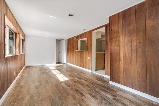 living room with baseboards, wood finished floors, and wooden walls