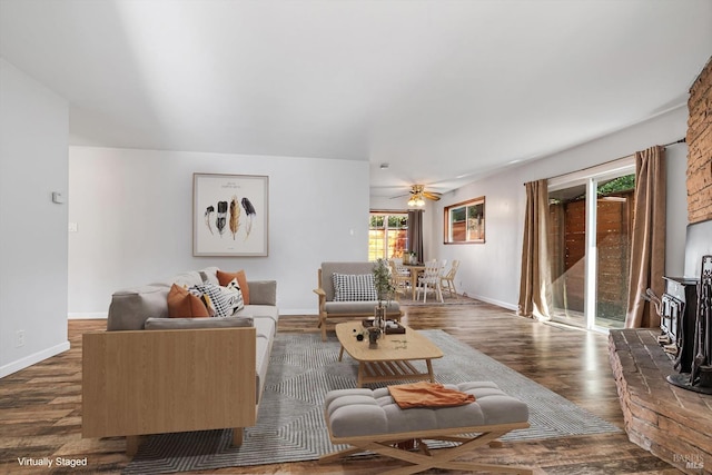 living area featuring a ceiling fan, baseboards, and dark wood-style floors