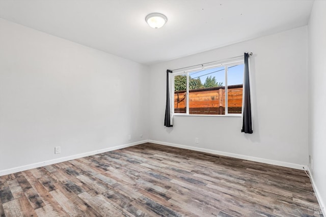 spare room featuring baseboards and wood finished floors