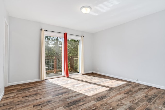 spare room with baseboards and wood finished floors