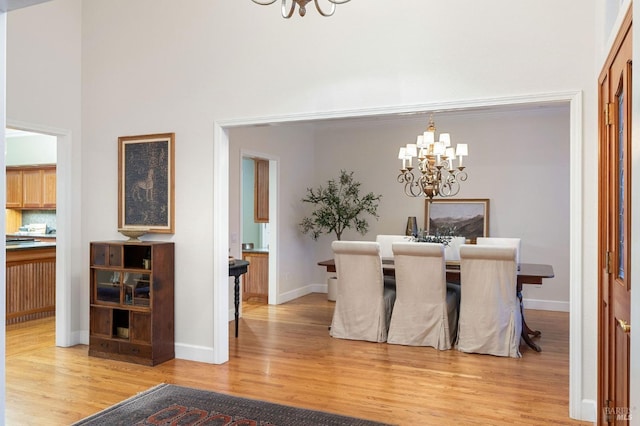 dining room with an inviting chandelier, baseboards, and light wood-type flooring