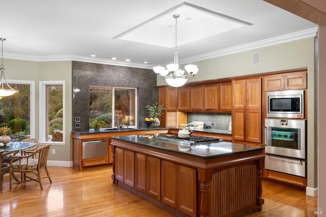 kitchen with a warming drawer, stainless steel appliances, ornamental molding, a chandelier, and a sink
