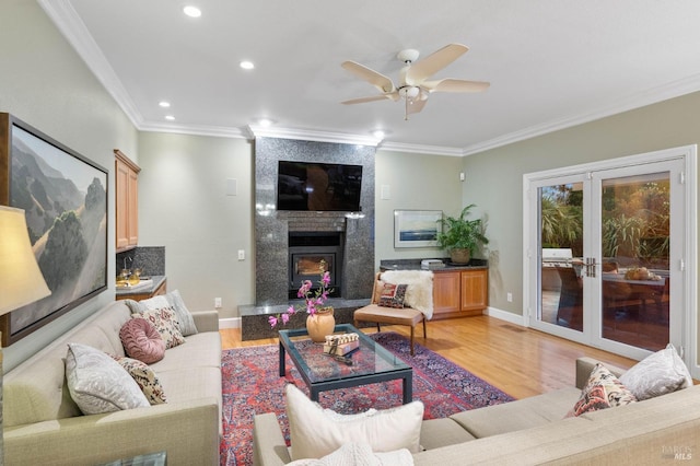 living area featuring baseboards, a ceiling fan, light wood-type flooring, and ornamental molding