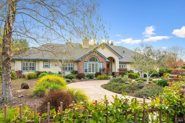 view of front of home with brick siding and curved driveway