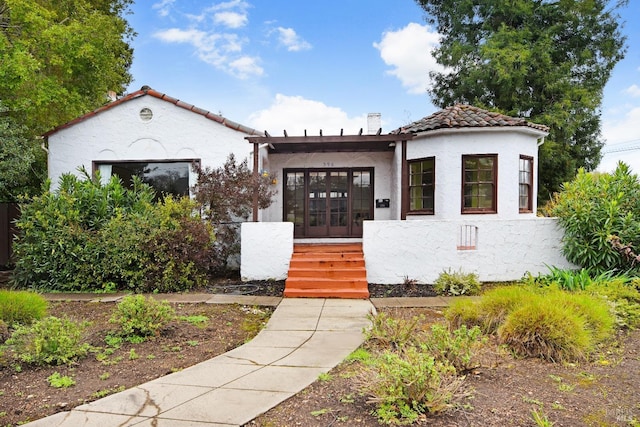 mediterranean / spanish house featuring stucco siding, a tiled roof, and french doors