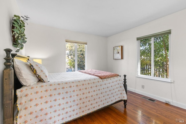 bedroom featuring wood finished floors, baseboards, and visible vents