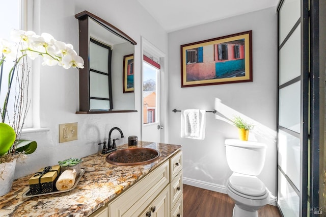 bathroom featuring toilet, wood finished floors, vanity, and baseboards