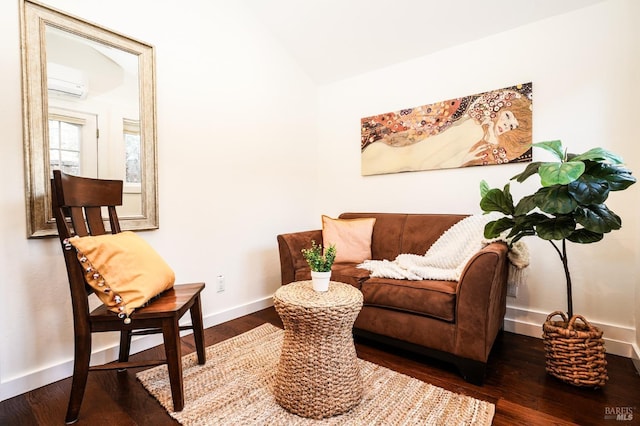 sitting room with a wall mounted AC, wood finished floors, baseboards, and lofted ceiling