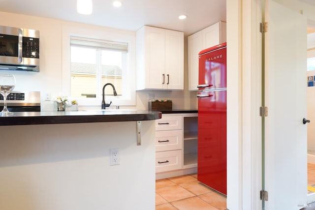 kitchen with light tile patterned floors, a sink, white cabinetry, recessed lighting, and stainless steel appliances