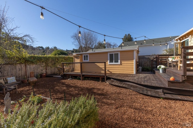 rear view of property featuring a patio area, fence, and a wooden deck