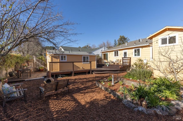 rear view of house featuring a vegetable garden, fence, and a deck