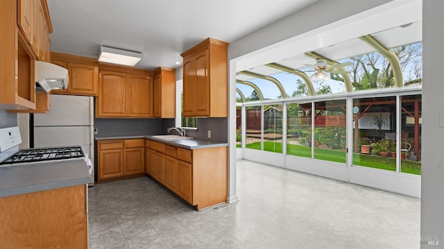 kitchen featuring a ceiling fan, range hood, a sink, and freestanding refrigerator