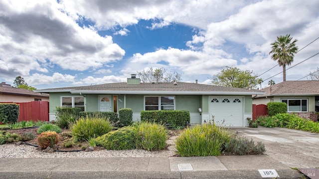 ranch-style home with driveway, a chimney, fence, a garage, and stucco siding