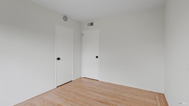 empty room with light wood-style flooring and visible vents