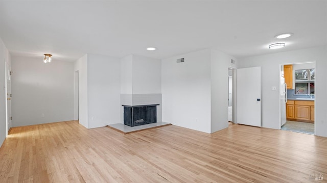 unfurnished living room with visible vents, light wood-style floors, a multi sided fireplace, and recessed lighting