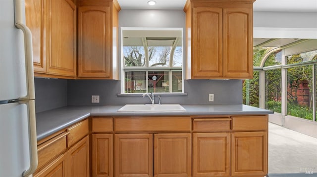 kitchen with light countertops, freestanding refrigerator, and a sink