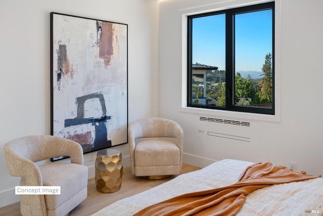 bedroom with a wall unit AC, multiple windows, and wood finished floors