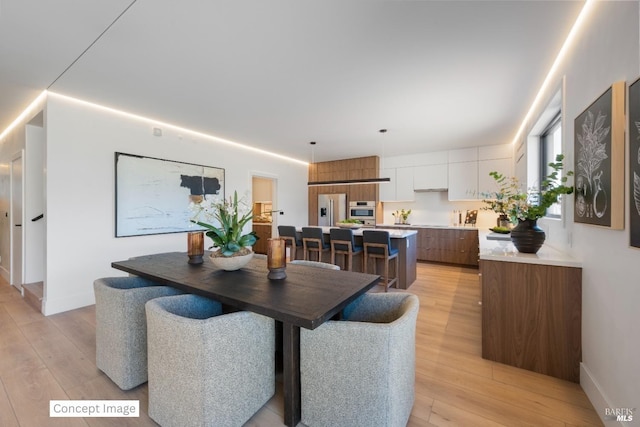 dining space with light wood-style flooring and baseboards