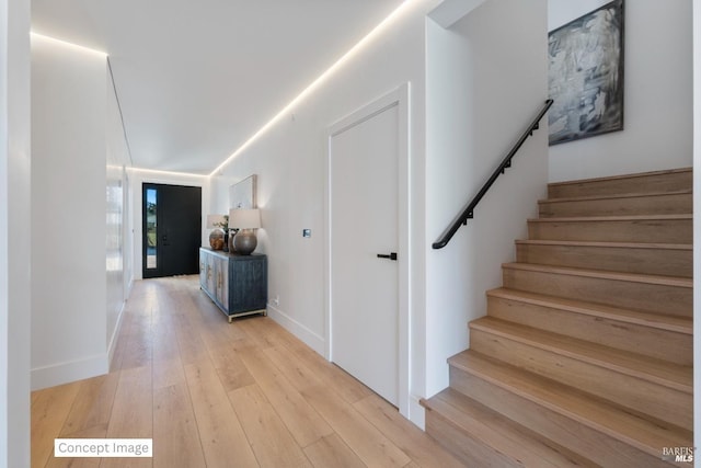 corridor featuring stairs, light wood-style floors, and baseboards