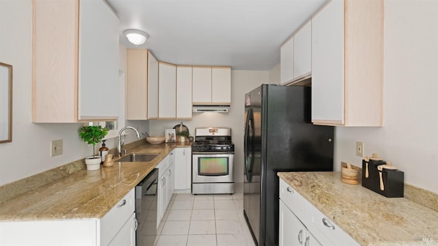 kitchen with a sink, stainless steel range with gas stovetop, under cabinet range hood, dishwashing machine, and freestanding refrigerator