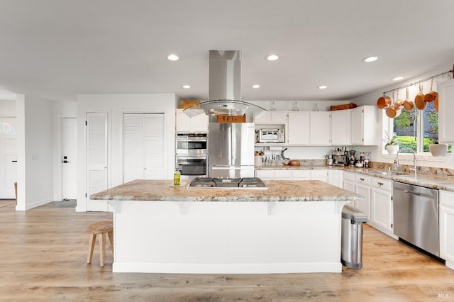 kitchen with a center island, a sink, island range hood, stainless steel appliances, and light stone countertops