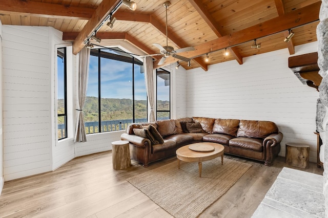 living area with wooden walls, wood finished floors, vaulted ceiling with beams, and wooden ceiling