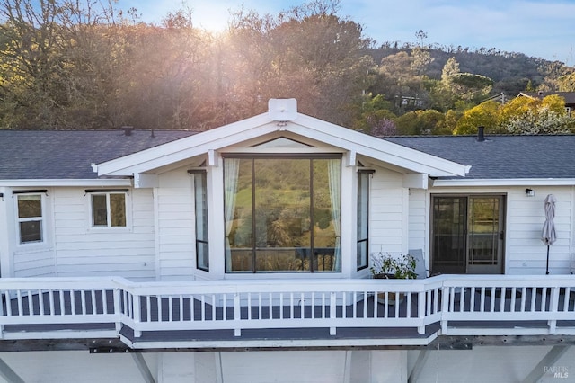 view of side of property featuring a wooden deck and a shingled roof