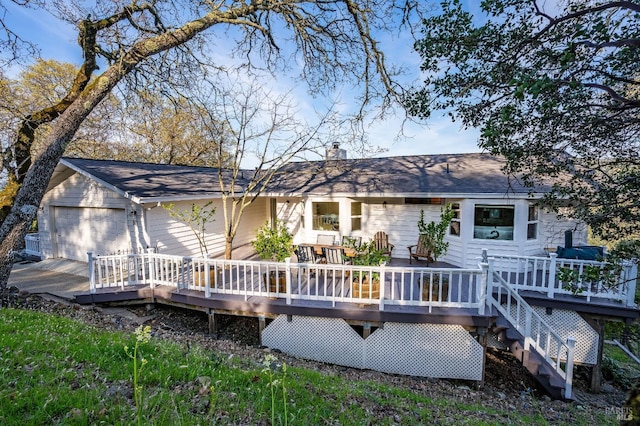 back of property with a chimney, a deck, and a garage