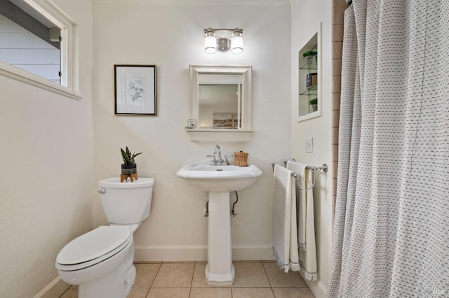 bathroom featuring a shower with curtain, toilet, baseboards, tile patterned floors, and a sink