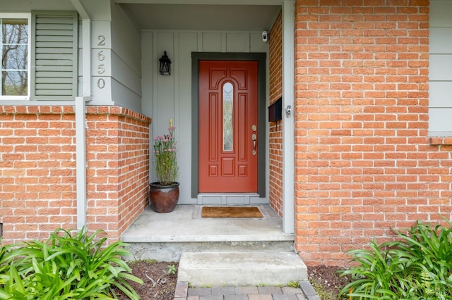 view of exterior entry with board and batten siding and brick siding