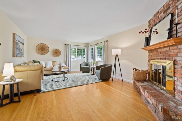 living area with baseboards, wood finished floors, and a brick fireplace