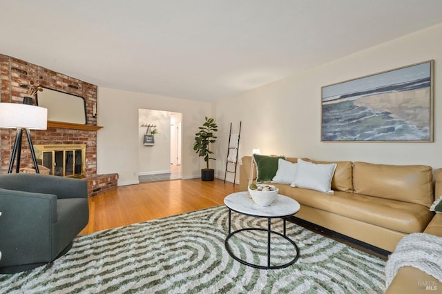 living area with baseboards, a fireplace, and wood finished floors