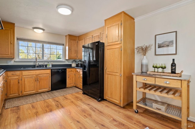 kitchen with light wood-style flooring, a sink, dark countertops, and black appliances