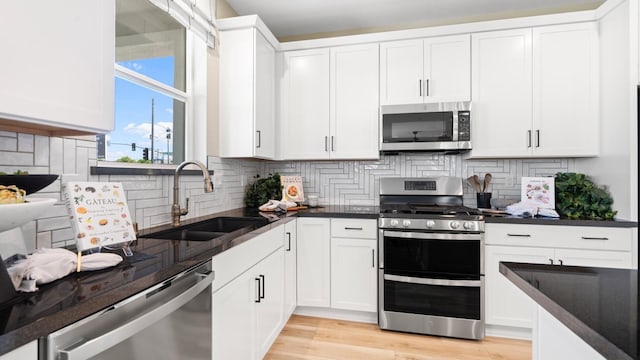 1096 Fiano Pl, Manteca, CA 95337 - kitchen featuring appliances with stainless steel finishes, a sink, backsplash, white cabinets, and light wood finished floors
