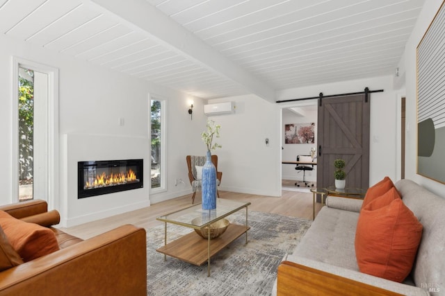 living room featuring a wall mounted air conditioner, a wealth of natural light, light wood-style flooring, and beamed ceiling