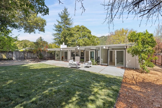 rear view of house featuring a fenced backyard, a lawn, stucco siding, and a patio